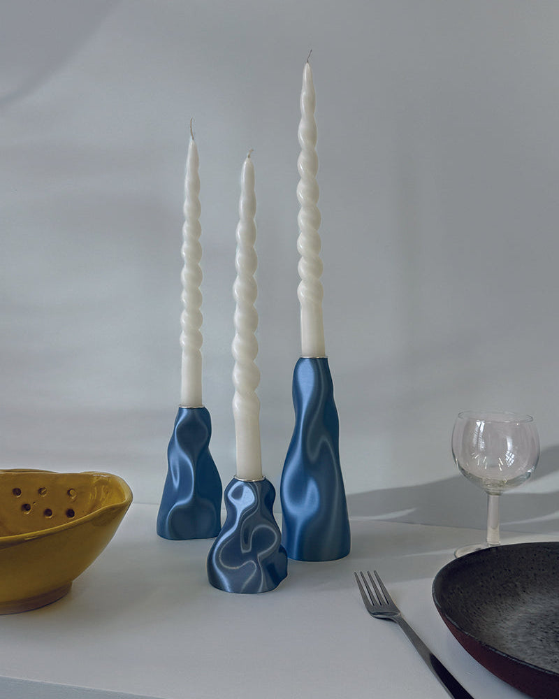 Blue candle holders with white candles on a light surface.