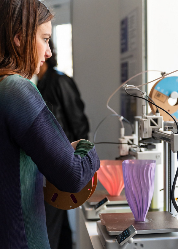 Person observing a 3D printing process in a laboratory setting.