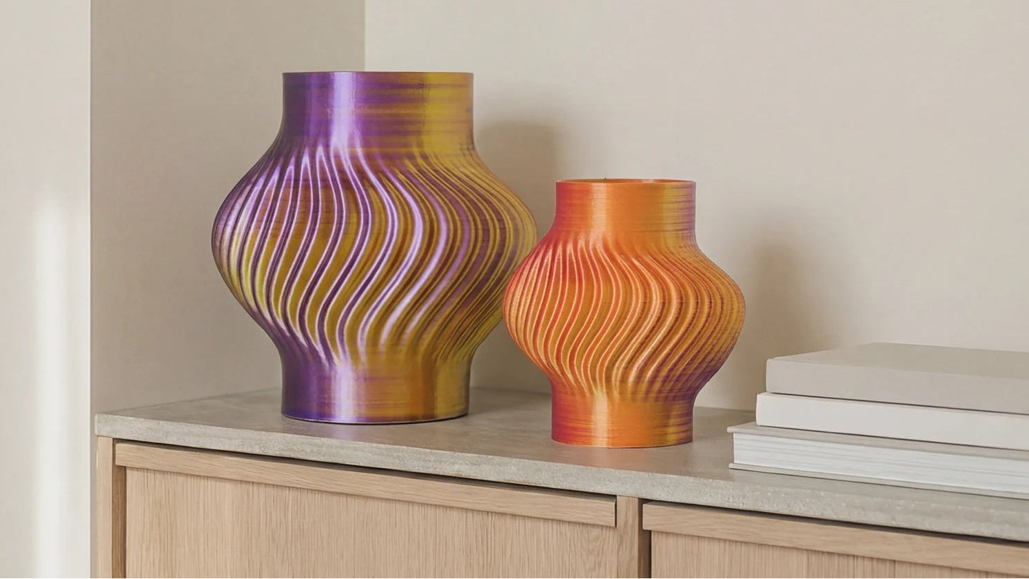 Two colorful vases on a shelf against a neutral wall.